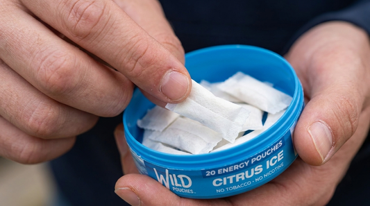Hand taking a Wild Pouches caffeine pouch from an open tin